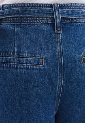 Denim jeans in medium blauw met een gestructureerde afwerking. Kenmerken zijn standaard achterzakken en contrasterende oranje stiksels langs de naden.