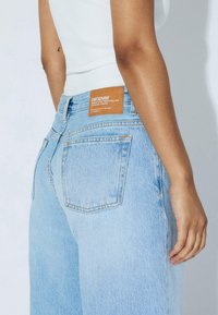 Light blue high-waisted jeans with a straight leg. Features a leather label on the back, stitched back pockets, and a faded wash.