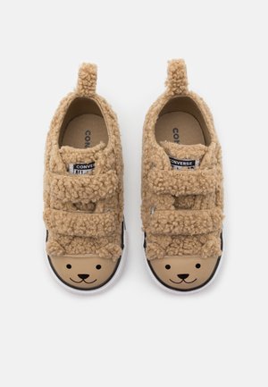 Zapatos difusos para niños pequeños de color marrón claro con dobles correas de velcro y caras de oso impresas en las punteras redondeadas, vistos desde arriba.
