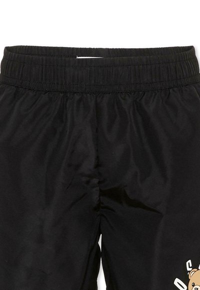 Pantaloni con vita elastica nera, tessuto liscio e una piccola grafica di un orsetto vicino alla parte inferiore della gamba destra.