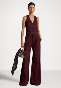 Μπορντό ραμμένο γιλέκο με κουμπιά, σε συνδυασμό με παντελόνι με φαρδιά μπατζάκια. Συμπληρώνεται με πολύχρωμο φουλάρι με διάφορα σχέδια και μικρό χιαστί τσαντάκι.