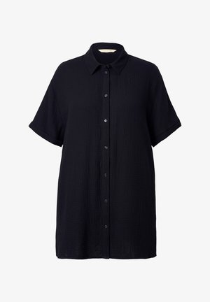 Musta lyhythihainen paita, joka on valmistettu teksturoidusta kankaasta. Paidassa on nappikiinnitys, terävä kaulus ja väljää istuvuutta.