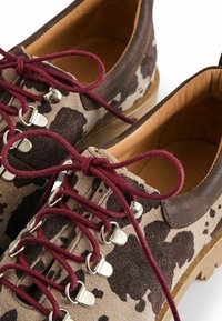 Ruskeat ja beige mokkanahkaiset vaelluskenkät, joissa on tummanruskea maastokuvio, viininpunaiset nauhat, hopeiset reiät ja pehmustettu vaaleanruskea nahkakaulus.