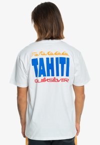 White cotton t-shirt featuring a large blue "TAHITI" graphic and red "Quiksilver" text on the back, accented with orange wave patterns.