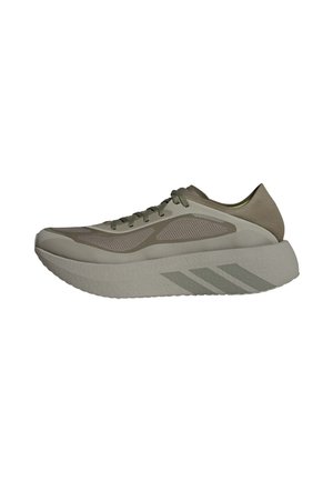 Hellbrauner Sportschuh mit dicker, gepolsterter Sohle, Mesh-Seitenteilen, Schnürverschluss und subtilem Streifenmuster auf der Sohle.