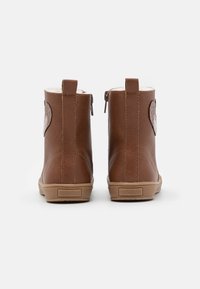 Bottines en cuir marron avec une finition texturée, ornées d'un motif de cœur pailleté et de zips latéraux, rehaussées d'une semelle en caoutchouc tan.