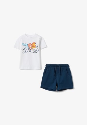 Camiseta blanca de manga corta con animales de dibujos animados y texto "STAY RAD", combinada con pantalones cortos azul marino con cinturilla elástica y bolsillos.
