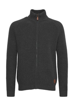 Zamek na szarym swetrze z dzianiny w kolorze antracytowym, z prążkowaną fakturą, wysokim kołnierzem i brązową skórzaną naszywką z logo w dolnym lewym rogu.