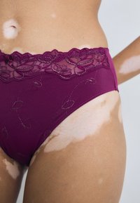 Burgunderfargede truser med blonder, dekorert med blomsterbroderier, har en jevn tekstur og et høyt livdesign.