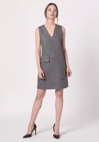 Vestido gris sin mangas con escote en V, que cuenta con dos bolsillos frontales con solapas. Hecho de una tela similar a la lana, tiene una silueta recta y un dobladillo.
