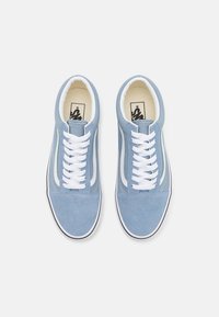 Une paire de baskets Vans bleu clair avec des lacets blancs et une bande sur le côté, vue d'en haut sur un fond blanc.