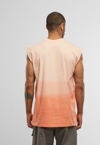 Ermeløs skjorte i en gradient fra lys pink til orange. Blødt stof, rund halsudskæring og løs pasform. Ingen synlige mønstre eller metaldele.