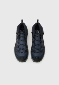 Sapatos de caminhada azul-marinho com parte superior em malha, bico de borracha reforçado e atacadores em contraste. Apresenta pegas para facilitar o calçar.