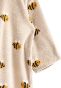 Tejido de forro polar con un fondo beige y un patrón de pequeñas abejas sonrientes en amarillo y negro, con mangas cortas y una textura suave.