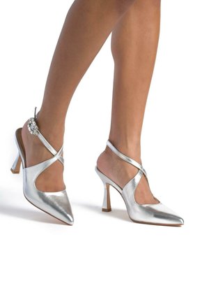 Décolleté slingback argento con punta affilata, finitura lucida, design a cinghia incrociata, piccola ferramenta decorativa e tacco a blocco di altezza media.
