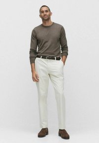 Ruskea pitkähihaisen neule, valkoiset housut, ruskea punottu vyö, ruskeat kengät. Slim-fit-muotoilu, sileä rakenne ja neutraali väri-ihannet.