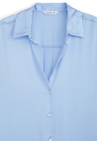 Camicia azzurro chiaro con colletto e bottoni davanti, etichetta del marchio "Terranova" in taglia piccola.