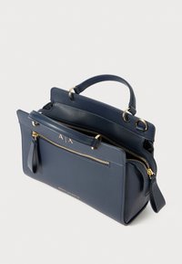 Sac à main en cuir bleu marine avec deux compartiments zippés, accents en métal doré et une poignée supérieure. Présente une texture lisse et un détail de marque.