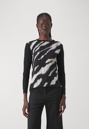Long-sleeve top with a black body and white abstract pattern, featuring a round neckline and soft fabric. Worn with black pants.