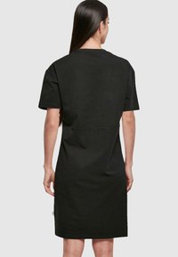 Czarna sukienka z krótkim rękawem wykonana z bawełny, o prostym kroju i minimalistycznym designie, z delikatnym detalem szwu z tyłu.