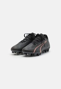 Scarpe da calcio nere con una finitura texturizzata, accenti rosa a contrasto e sei tacchetti per una migliore aderenza. Presentano allacciatura tradizionale e un design elegante.