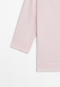 Light pink long sleeve sweater section showing the cuff and bottom hem on a plain white background.