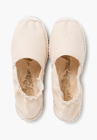 Scarpe slip-on in tela beige chiaro con punta arrotondata, aperture elastiche e suola testurizzata. Presentano un bordo cucito lungo il perimetro.