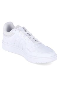 White athletic shoe with a smooth leather upper, mesh accents, rounded toe, lace-up design, and a textured rubber sole.