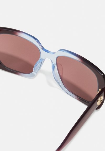Ochelari de soare cu un cadru transparent nuanțat albastru, lentile nuanțate roșu închis și un accent auriu pe tâmple; formă unghiulară cu o textură netedă.