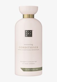 Botella de acondicionador restaurador, color rosa pálido, forma redonda, acento dorado alrededor del cuello, logo emblema, texto que indica su idoneidad para cabello dañado y teñido.