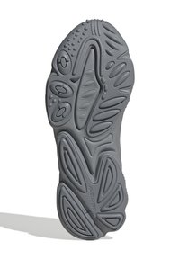 Sole di scarpa da ginnastica grigia con gomma testurizzata, caratterizzata da motivi vari, scanalature e accenti circolari. Nessun marchio visibile sulla parte inferiore.