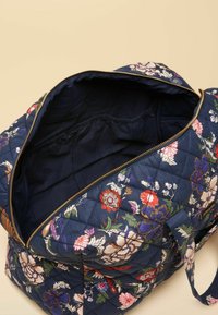 Granatowa pikowana torba z kwiatową haftem w kolorach czerwonym, różowym i fioletowym. Posiada złoty zamek błyskawiczny i materiałowe uchwyty. Wnętrze wyłożone ciemną tkaniną.