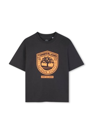 T-shirt en coton noir avec col rond. Présente un badge graphique orange avec le texte "TIMBERLAND", le logo de l'arbre, et "OUTDOOR UTILITY".