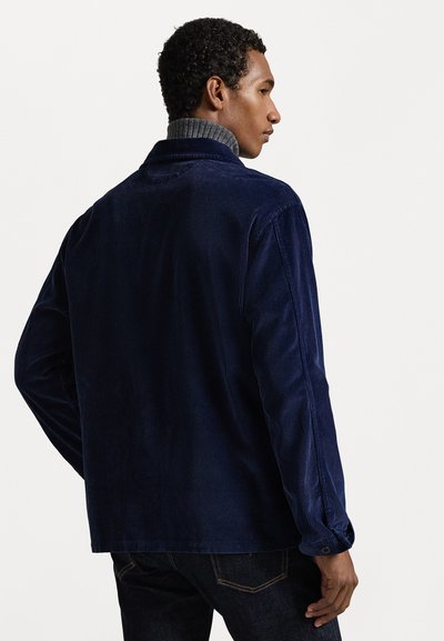 Μπλε κοτλέ πανωφόρι με άνετη γραμμή, που διαθέτει γκρι ραμμένο γιακά και μακριά μανίκια, ορατές ραφές και λεπτομέρειες κουμπιού στους καρπούς.