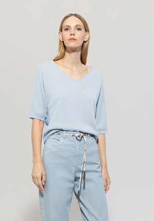 Light blue short-sleeve V-neck sweater in a soft texture, paired with light blue pants featuring a patterned belt tied in a bow.