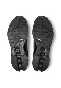 Semelles de chaussures de sport noires avec une texture en caoutchouc antidérapant, arborant un motif hexagonal et une bande d'accent bleu. Rembourrage en mousse durable visible.