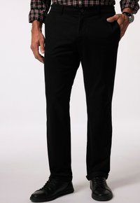 Svarta byxor med rak passform, tillverkade av bomullstyg. Med knappknäppning, framfickor och uppvikta fållar. Bärs med svarta sneakers.