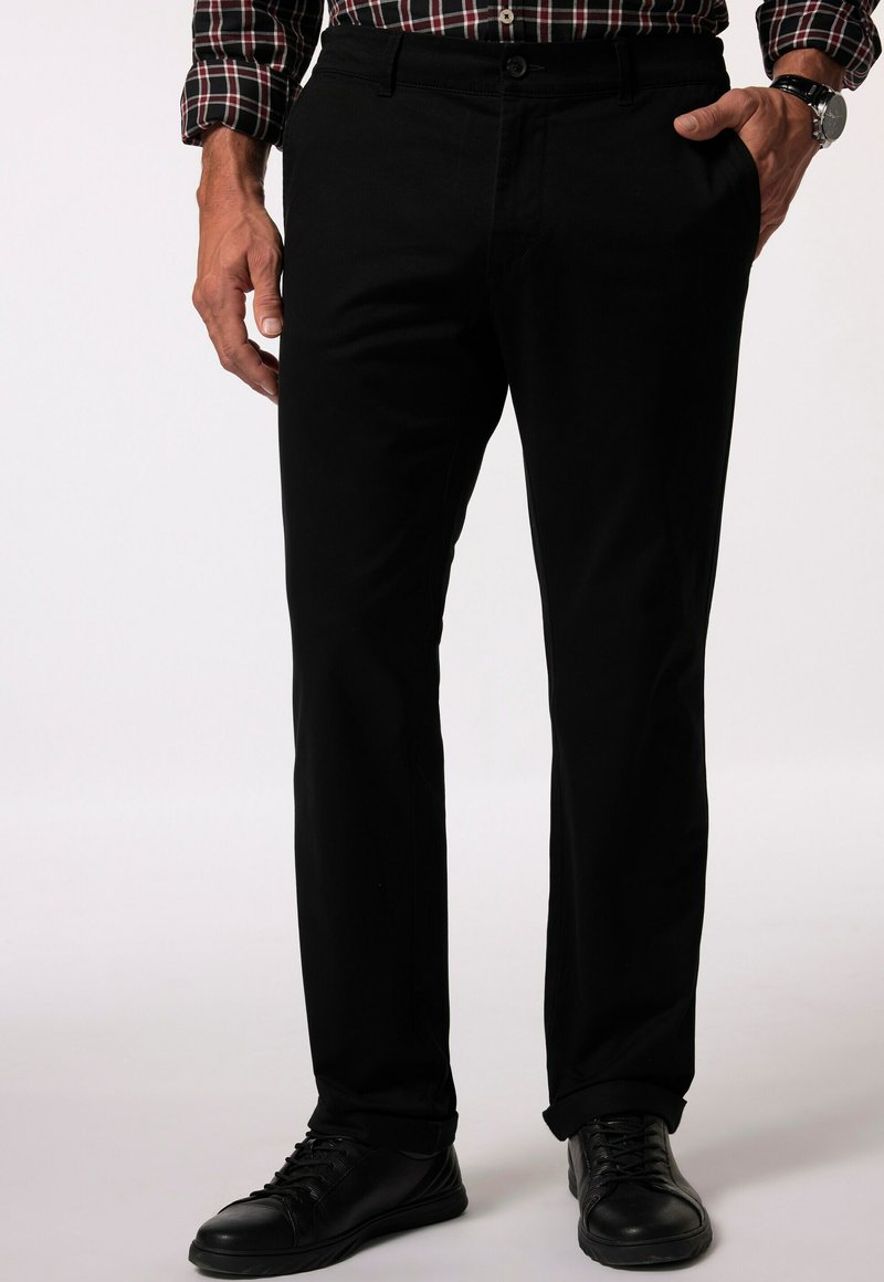 Svarta byxor med rak passform, tillverkade av bomullstyg. Med knappknäppning, framfickor och uppvikta fållar. Bärs med svarta sneakers.