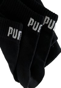 Black socks with ribbed texture, featuring "PUMA" in grey knit embroidery on the cuff. Four pairs stacked in a neat arrangement.