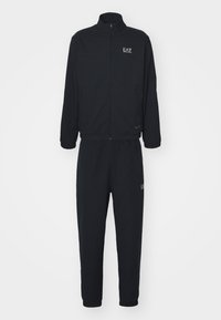 Zwart trainingspak met textuurstof, jack met ritssluiting en broek met elastische tailleband. Bevat EA7-logo op de borst en dij. Eenvoudig, functioneel ontwerp.