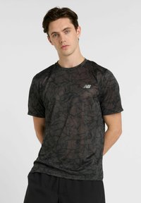 Black athletic t-shirt featuring a geometric pattern, short sleeves, round neckline, and a small reflective logo on the left chest.