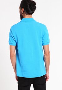 Ljusblå polo skjorta med korta ärmar, tillverkad av ett mjukt bomullsmaterial. Har en klassisk krage och en rak nederkant.