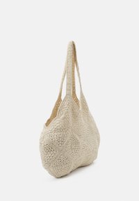 Gehaakte tas in beige, met een textuur van een diamanten patroon, zachte vorm en dubbele platte hengsels om te dragen.
