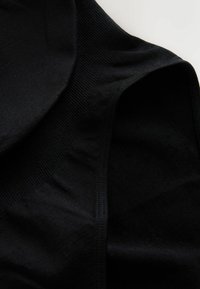 Sort bomuldstanktop med ribbet halsudskæring og glat stoftekstur. Designet er tætsiddende med få syninger.