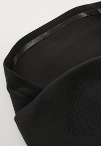 Tissu élastique noir au toucher lisse avec une bande noire brillante. Présente un motif texturé, replié sur un bord.