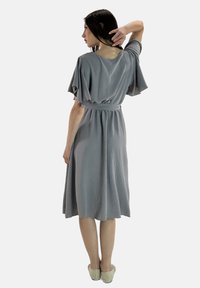 Robe grise avec des manches flottantes, taille cintrée et une silhouette jusqu'aux genoux. Texture douce, design minimaliste, sans motifs ni accents.