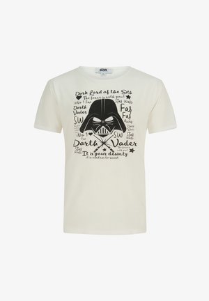 T-shirt en coton crème présentant un grand motif noir de Dark Vador, avec divers éléments textuels et des étoiles autour du design.