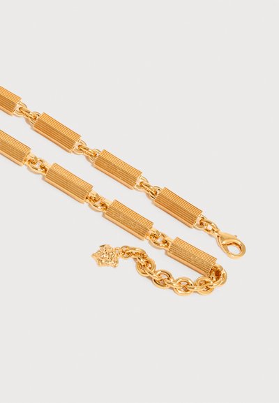 Χρυσό κολιέ με αλυσίδα από ορθογώνιους υφασμένους κρίκους και κούμπωμα λαβίδα, με ένα μικρό μενταγιόν κεφάλι λιονταριού κοντά στο τέλος.