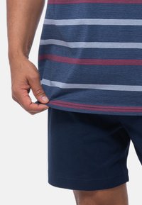 Laivastonsininen lyhythihainen paita, jossa on vaakasuoria raitoja punaisena, valkoisena ja sinisenä. Yhdistetty laivastonsinisiin shortseihin; pehmeä puuvillakangas näkyvissä.