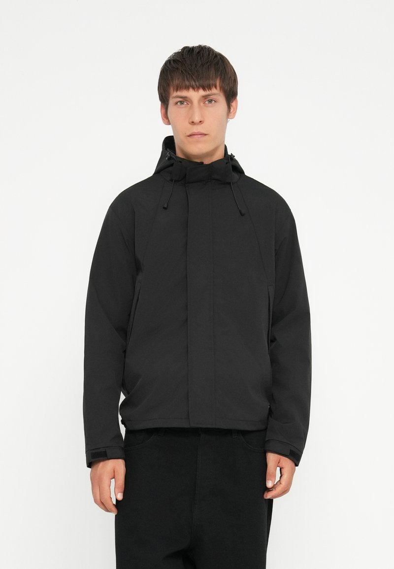 Schwarze, kapuzenjacke aus leichtem Material, mit einem vorderen Reißverschluss, verstellbaren Kordeln und einem lockeren Schnitt. Glatte Textur, keine Muster.